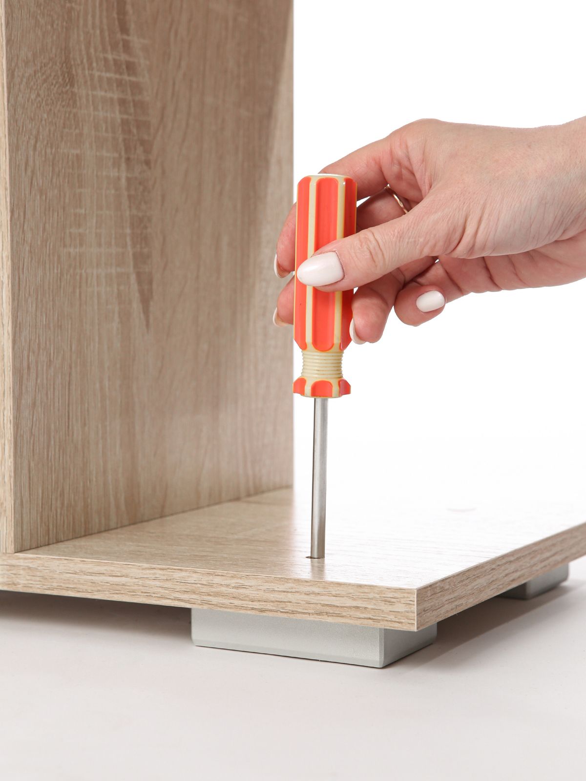 A hand using a screwdriver to assemble a wooden furniture panel